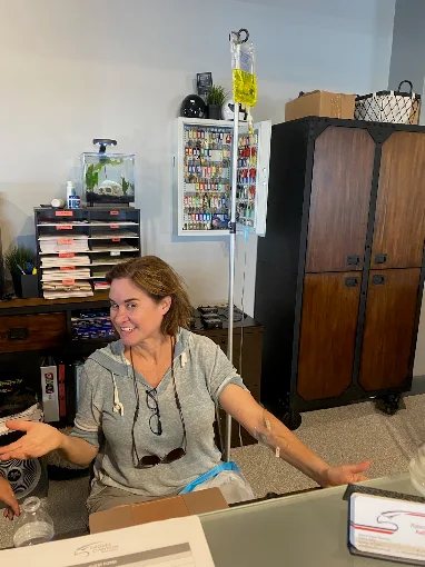 A smiling client at her office desk during a mobile IV visit