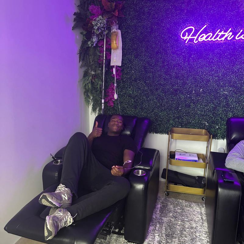 A client giving a thumbs up, feet up in a recliner at the studio
